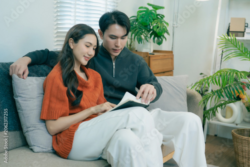 Εκτύπωση καμβά A happy young Asian couple sits together on a sofa at home
