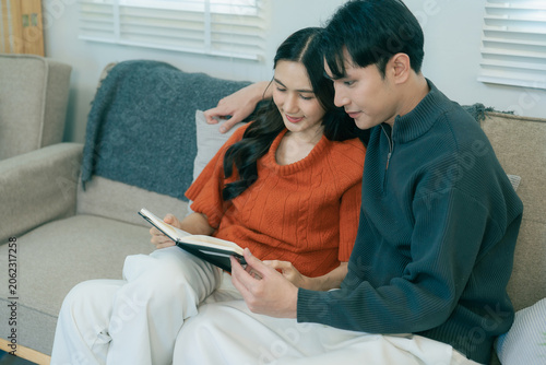 Принти на полотні A happy young Asian couple sits together on a sofa at home