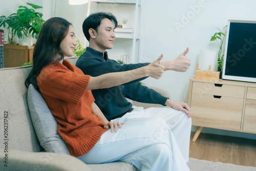 Принти на полотні A happy young Asian couple sits together on a sofa at home