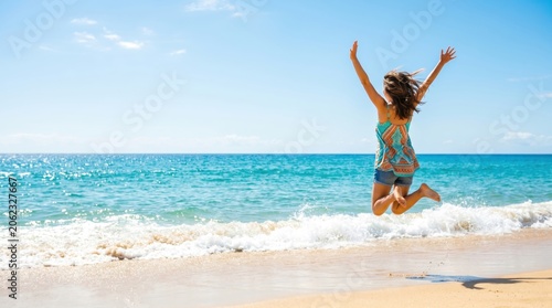Joyful Woman Jumping on Tropical Beach by Turquoise Ocean With Copy Space