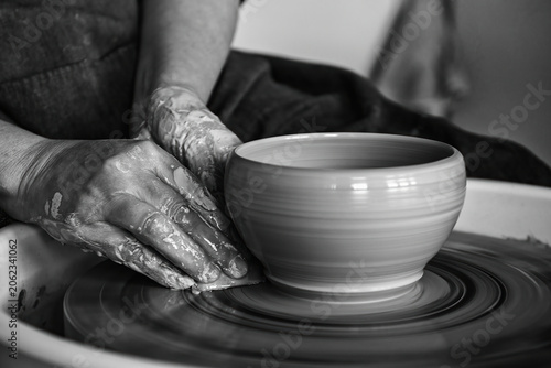 potter models the clay on a potter's wheel