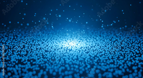 Glowing blue light shines through numerous small particles on a dark surface.
