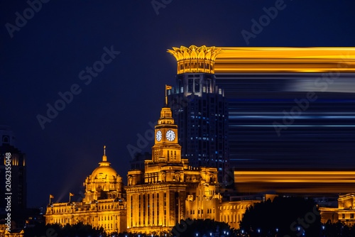 Fotografie A dramatic night view of the Shanghai skyline featuring illuminated historic architecture and modern skyscrapers