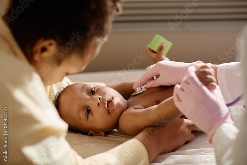 Portrait of Black baby receiving pediatric checkup while mother supporting during doctor examination, showing child healthcare and preventive care use for clinic marketing