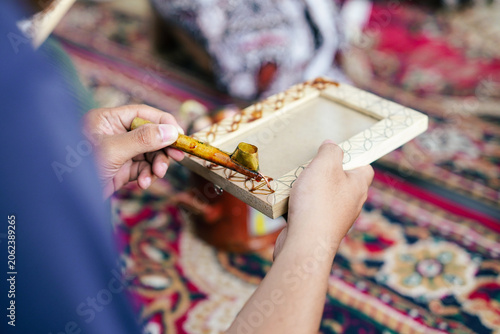 Φωτογραφία Skilled artist applying batik wax to a wooden picture frame, highlighting tradit