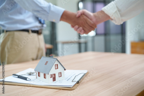 Photos Real estate transaction with handshake and miniature house model
