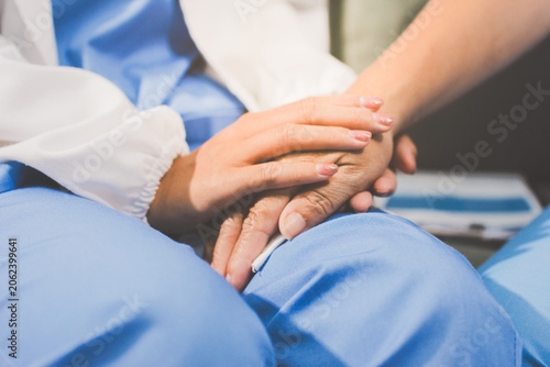 Compassionate healthcare provider holds the hand of an elderly patient to offer support and comfort.