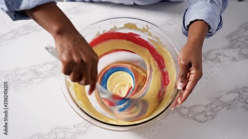 Colorful Batter Mixing Creating Swirl Pattern In Glass Bowl On Marble Surface