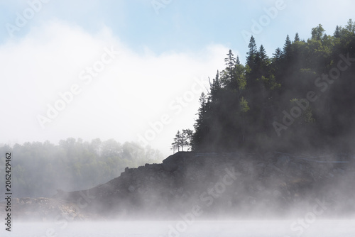 Quadro su tela Fog drifting over rocky Bureya Reservoir shoreline with sparse trees and a soft