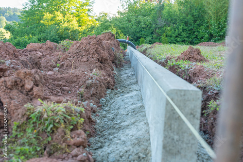 Concrete border line installation on a hill. Long concrete lawn edging with fresh mortar
