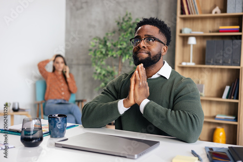 Obraz na plátne Black man praying for help in office during stressful work