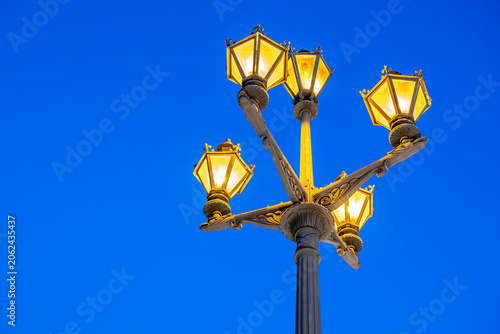 Light poles shine under clear blue sky in city