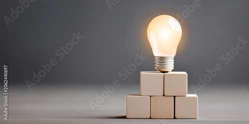 Illuminated Idea: A glowing lightbulb rests atop a pyramid of stacked wooden blocks, symbolizing innovation, creativity, and the birth of a bright new concept.