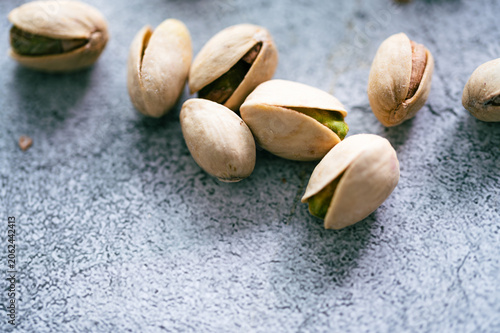 Принти на полотні Whole roasted pistachio nuts in shells scattered on a blue textured background,C