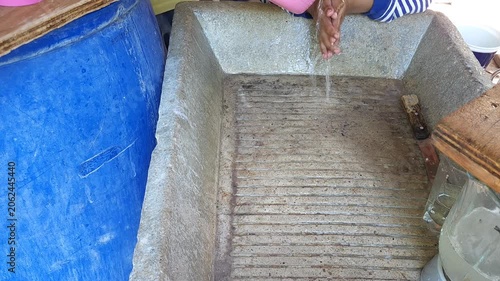 Mother Washing Young Child Hands in Concrete Laundry Sink Outdoors