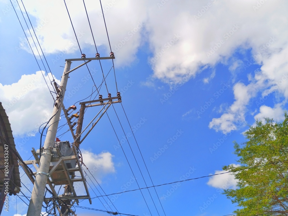 Fototapeta premium Electrical utility pole with transformer and power lines under bright blue sky infrastructure
