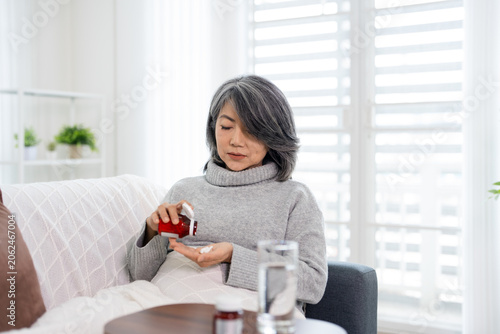 Foto woman sitting on the sofa at home, feeling unwell, and took medicine with a glass of water to treat her illness