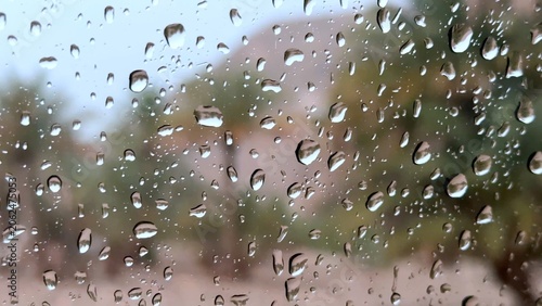 Cuadro en lienzo Raindrops on window with blurred garden and house beyond