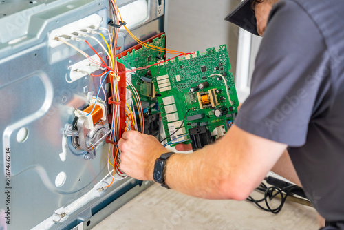 Tableau sur toile Appliance technician replacing faulty electronic control board inside electric oven