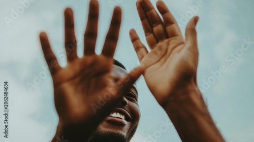 Joyful African American man's elated expression with hands raised towards the sky showing positivity
