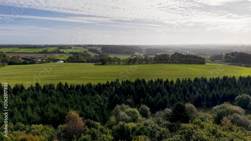 Aerial drone view of agricultural farmland and forested countryside across the Jutland region of Denmark