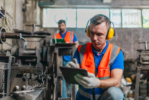 Foto Factory Technicians Reviewing Machine Maintenance Checklist in Metal Workshop