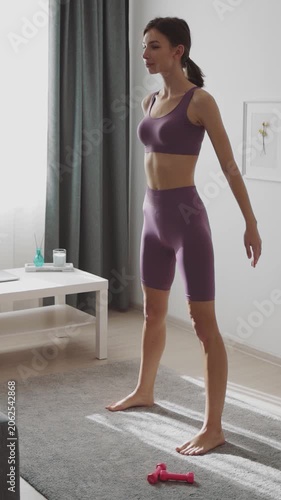 Woman exercises at home with a focus on squats using a simple setup in a living room.