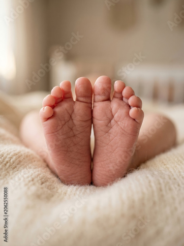 Cute tiny newborn baby feet close up photography on white blanket