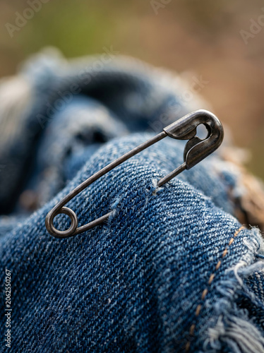 Classic safety pin attached to classic blue denim jeans fabric