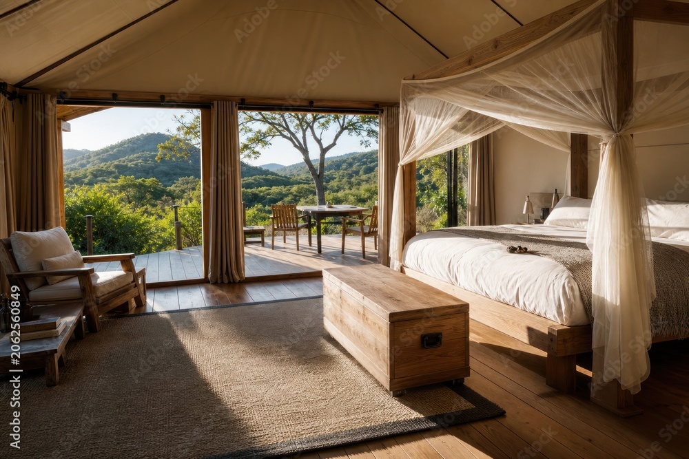 Obraz premium Safari tent suite interior with elegant canopy bed and wooden deck overlooking scenic green hills, peaceful eco lodge glamping experience