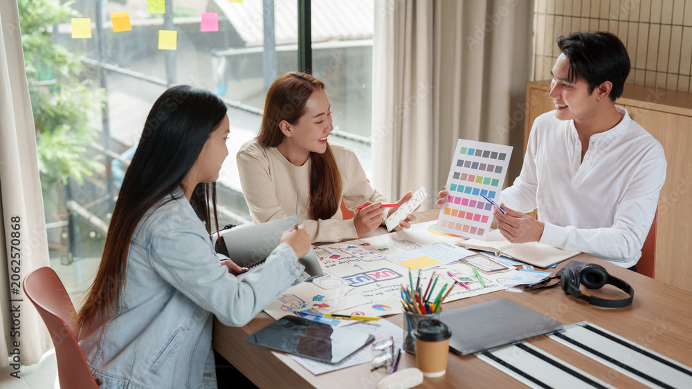 Fototapeta premium Asian creative design team brainstorming mobile app interface in office