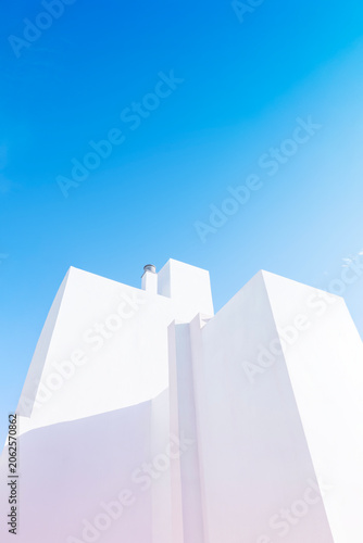 A striking example of minimalist architecture. The clean, angular lines of the white building are softened by natural sunlight and shadows, creating a simple yet powerful and aesthetic composition.