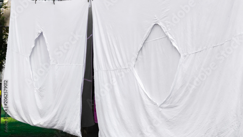 Photos White duvet covers with diamond shape hole hanging on a clothesline closeup