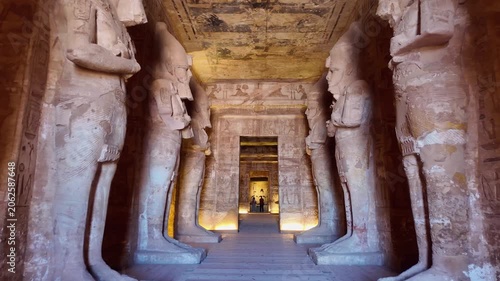 First person view (POV) walking through Ancient egyptian statues of ramesses ii lining the great hypostyle hall of the abu simbel temple. Famous landmark and historical site in nubia