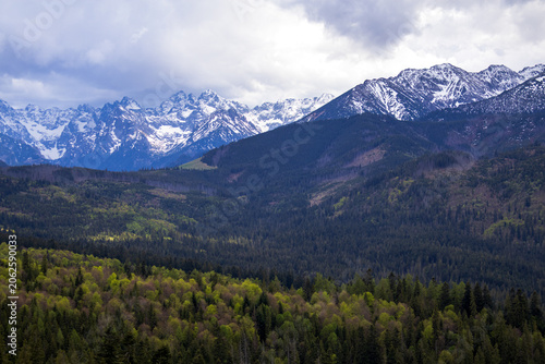 Panoramic view of snow covered High Tatras mountains under changing spring weather. Dramatic alpine landscape, natural beauty and tourism destination in southern Poland.