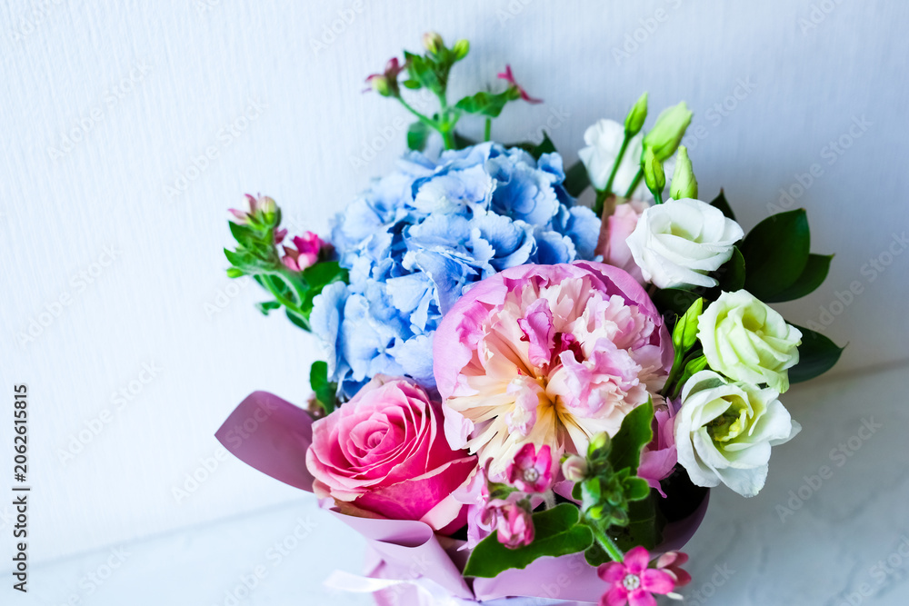 Fototapeta premium Flowers in a bouquet with blue and pink blooms arranged in a simple style on a light background during daytime