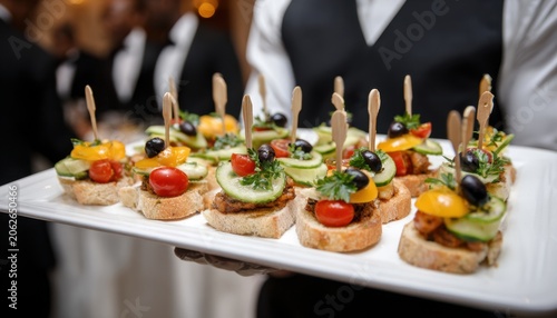 Gourmet bruschetta appetizers served on a white platter by a waiter at a catering event or wedding reception