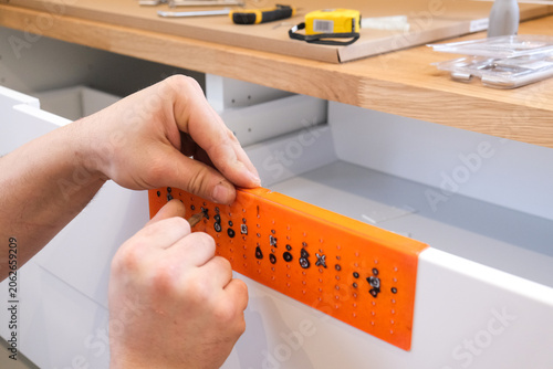 Canvastavla Person attaching drawer slide jig to white kitchen cabinet drawer