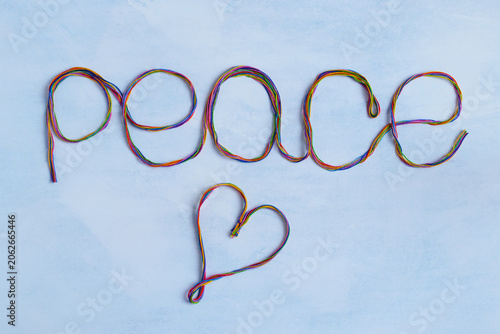 Top view on inscription Peace and heart from colorful threads on light gray background. Symbol of love and peace.