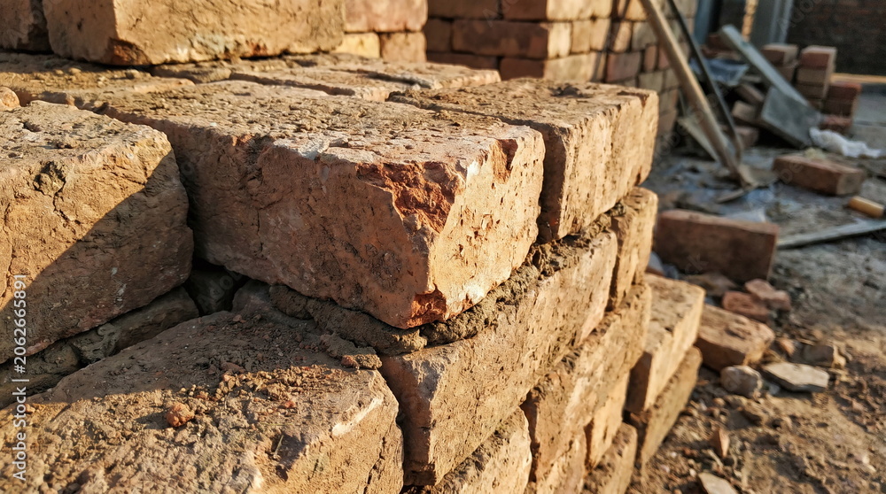 Fototapeta premium Stack of old red clay bricks with mortar at a construction site