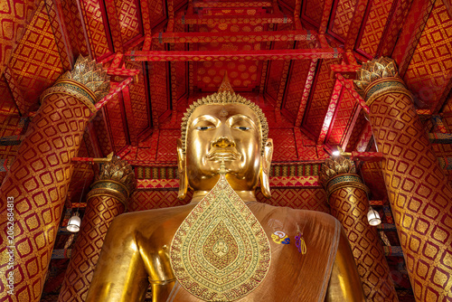 Giant Buddha statue inside the temple of Wat Phanan Choeng, in Ayutthaya Thailand. Surrounded by Beautifully decorated walls and pillars. 
