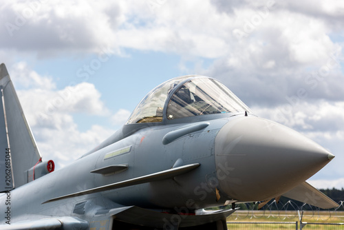 Bild auf Leinwand Modern fighter 4th generation jet airfield sleek aerodynamic nose transparent cockpit canopy dramatic clouds sky