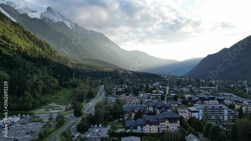4K Aerial Take‑Off Drone View of Alpine Town in Mountain Valley with Snow‑Capped Peaks and Forest Under Morning Light and Cloudy Sky, Haute‑Savoie, French Alps, France