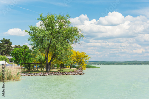 Hungary, Lake Balaton, view of the lake shore with green trees above the water on a sunny summer day.