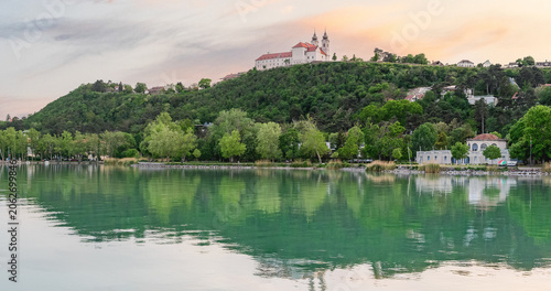 Hungary, Tihany, Benedictine monastery on a hilltop with reflection in the water, evening view from the port on Lake Balaton.