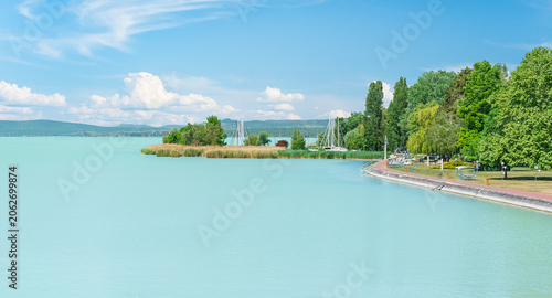 Hungary, Lake Balaton, view of the lake shore with green trees above the water on a sunny summer day.