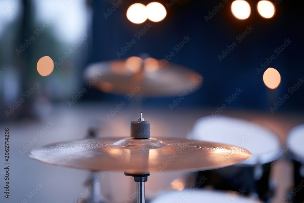 Fototapeta premium Warmly lit golden cymbal on a drum set with soft bokeh lights in the background