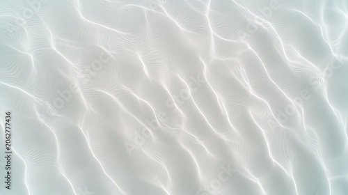 Aerial view of shallow tropical water with sunlight reflecting on the sandy seabed creating wavy patterns