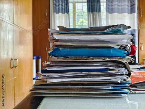 Stack of Papers on Desk with Curtains in Background