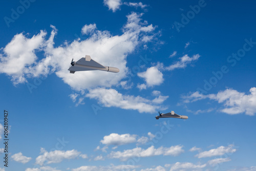 3d render of Shahed style one-way attack drones in front of blue sky with clouds. Selective focus on closest drone